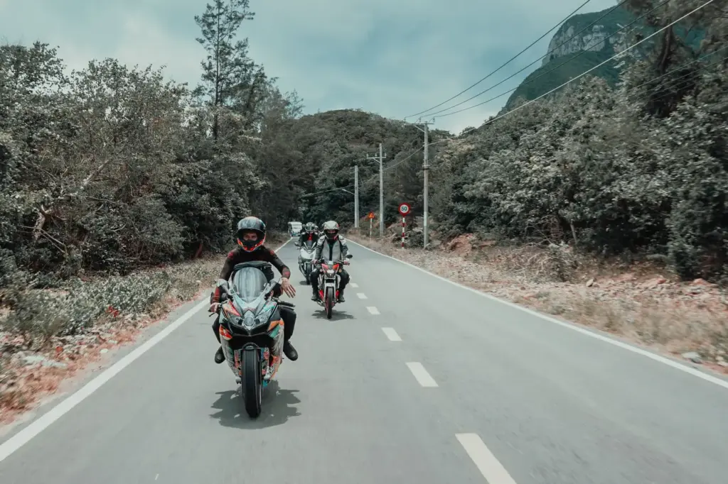 A group of motorcyclists riding in a staggered line along a country road