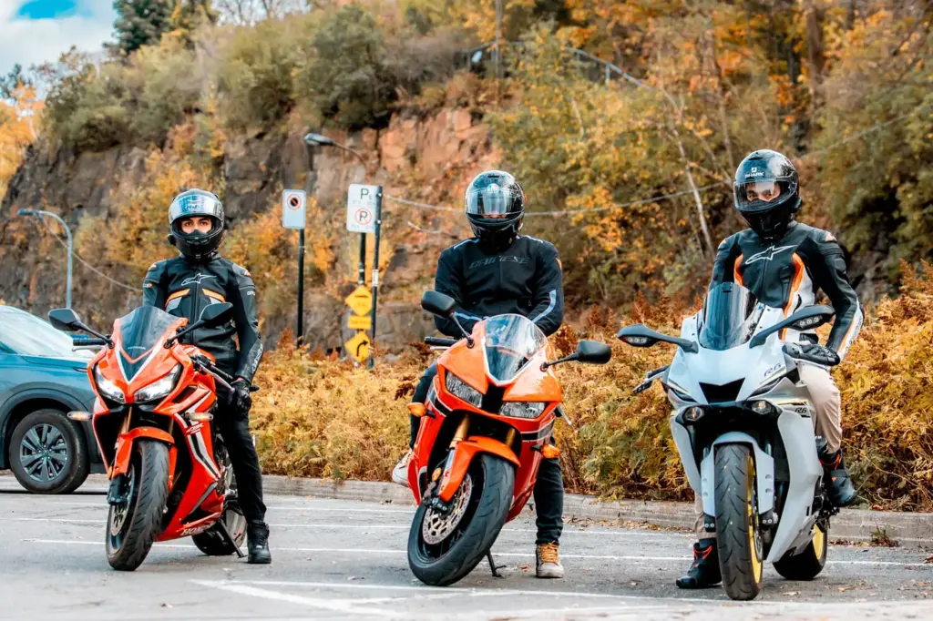 Three riders with their sport bikes during a roadside stop in autumn